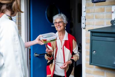 Dame opent deur en ontvangt een maaltijd