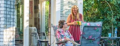 Medewerker van de Zonnebloem en klant gezamenlijk aan de koffie in de tuin. Medewerker van de Zonnebloem en klant gezamenlijk aan de koffie in de tuin.