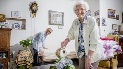 Klant en thuishulp gezamenlijk aan het werk. Mevrouw geeft de plantjes water.